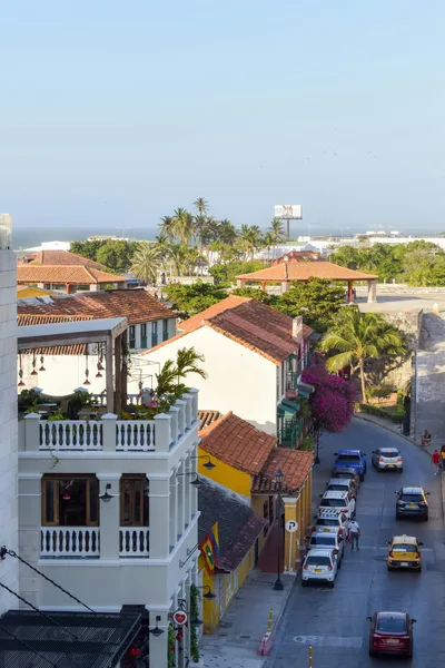 Aerial view of a charming tropical town with palm trees, rooftops, and a lively street scene.