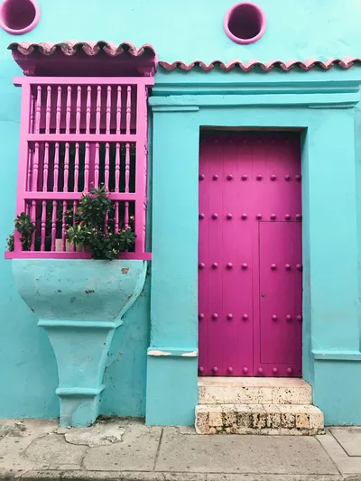 Vibrant pink and turquoise facade in Cartagena, Colombia showcasing colonial architecture.
