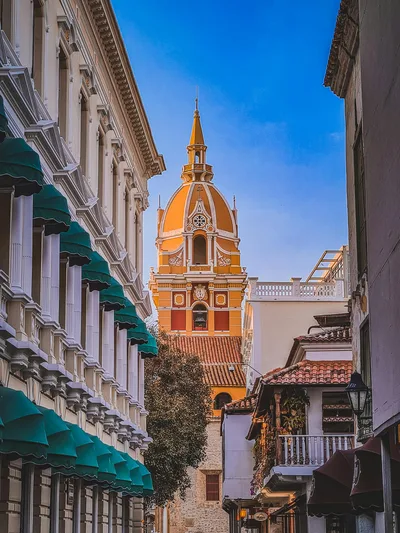 Charming view of Cartagena's colonial architecture with vibrant colors and detailed design in a narrow alleyway.