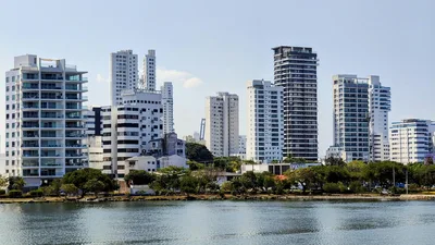View of Cartagena's high-rise buildings reflecting in water under a clear sky.