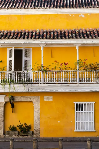 Charming yellow colonial building with balcony in Cartagena, showcasing vibrant architecture.